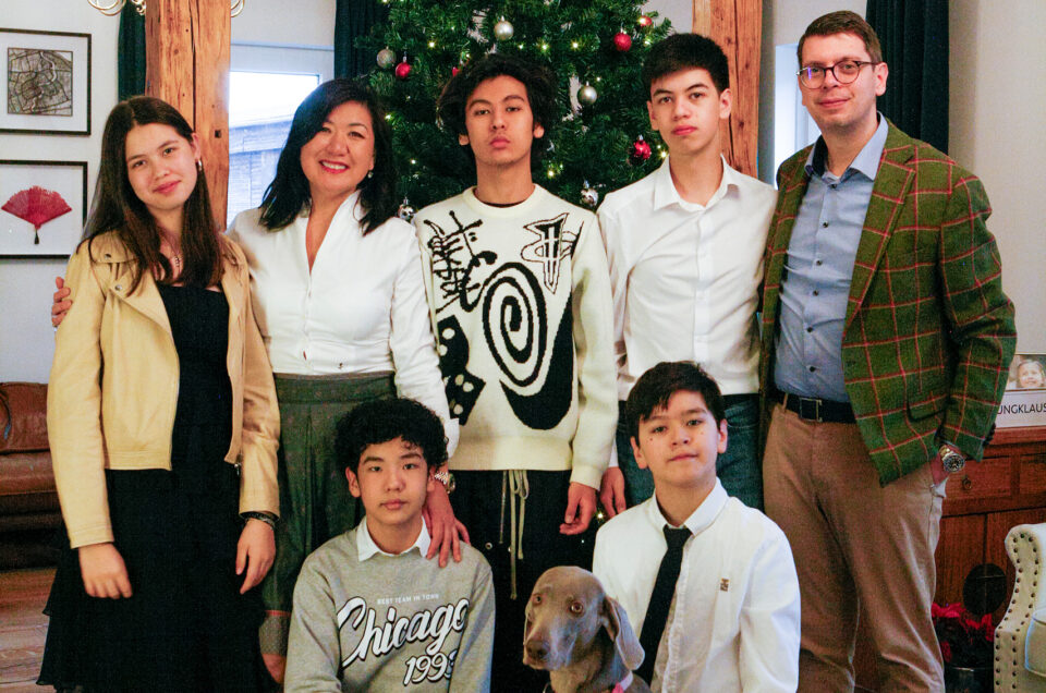 Familienfoto zu Weihnachten – Eltern und Kinder mit Hund vor Weihnachtsbaum, aufgenommen bei einem natürlichen Indoor-Fotoshooting.