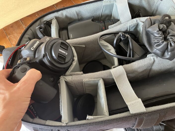Das Foto zeigt wie jemand eine Kamera aus einer Kameratasche rausholt. Es soll zu einem Fotocoaching einladen.