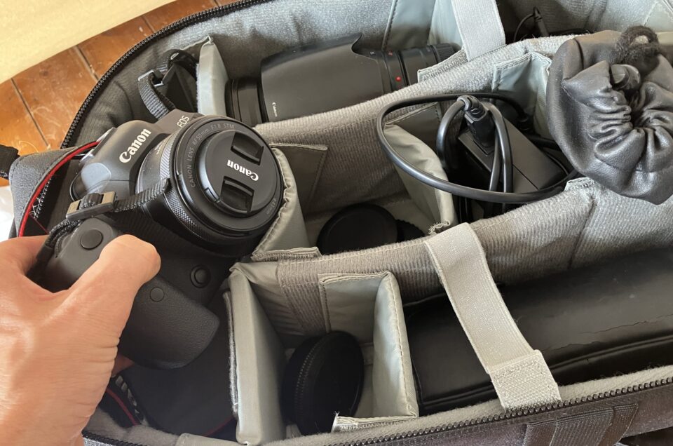 Das Foto zeigt wie jemand eine Kamera aus einer Kameratasche rausholt. Es soll zu einem Fotocoaching einladen.
